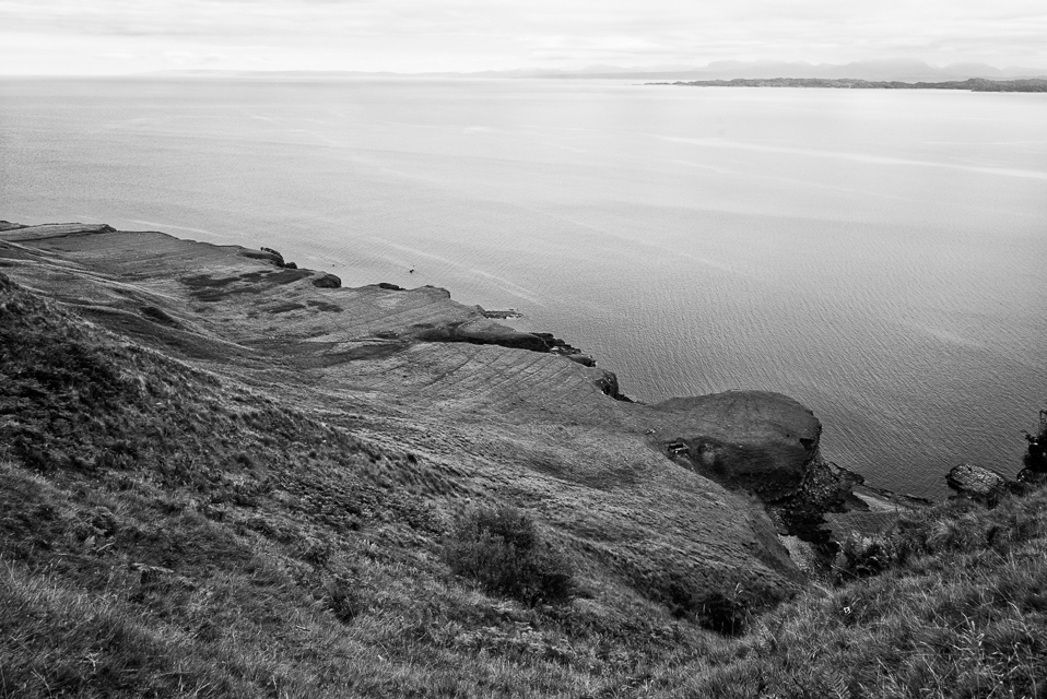 View of the north-east coast of the Isle of Skye. The land here falls down, not so gently, from the road and walking pathways to the sea. There are sheep grazing along the coast here.